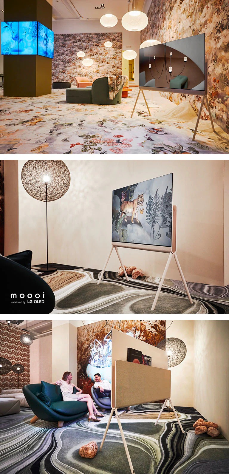 Posé gezien als deel van Moooi's Divine Dreams Collectie met een afbeelding van een modern interieur op het scherm, en omgeven door decor met vlinders en bloemen en wolken. Posé van voren gezien als deel van Moooi's Defy Gravity Collectie met een tijgerkunstwerk op het scherm, en bovenop een tapijt met steenmotief. Posé van achteren gezien als deel van Moooi's Defy Gravity Collectie met boeken met ruimtethema die in de Organisateur de câbles et d’accessoires worden vastgehouden. Moooi bedacht door LG OLED logo.