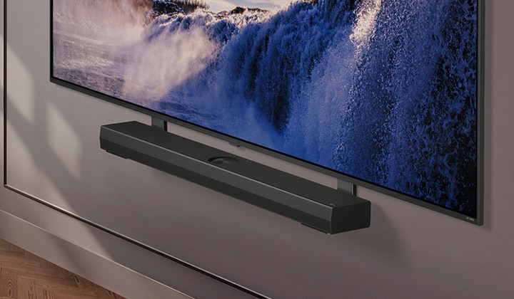 Synergy-beugel met LG QNED TV. Synergy-beugel en LG QNED TV zijn met elkaar verbonden en het beeld gaat naar de onderkant van de tv. LG Soundbar verschijnt terwijl deze op de Synergy-beugel wordt geplaatst. De achtergrond verschijnt met de muur.