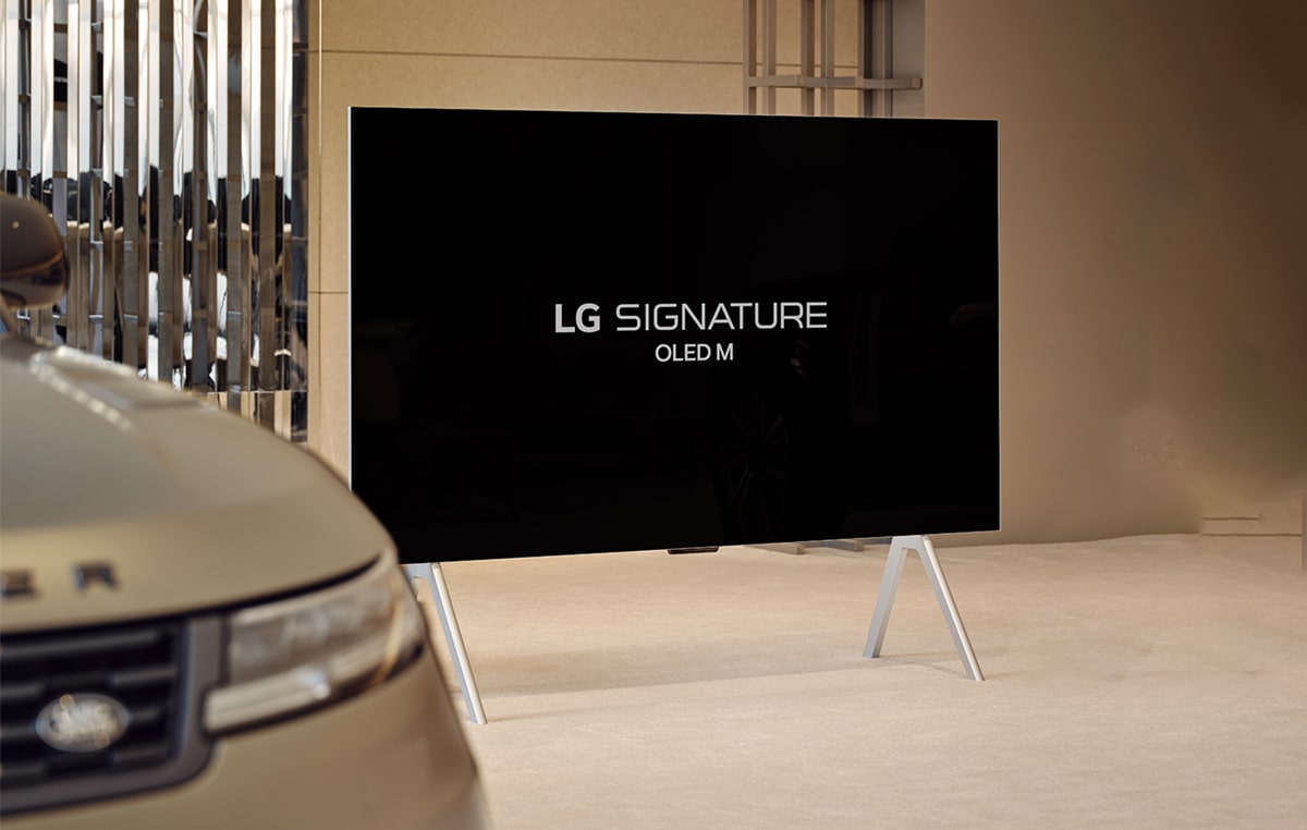 LG SIGNATURE OLED M4 op een standaard in het Range Rover House naast de Range Rover Sport SV, en een afspeelknop onder in beeld.