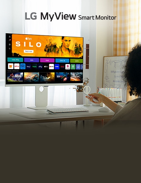 Een vrouw zit voor een smart-monitor op de tafel en drukt op knoppen van de afstandsbediening.