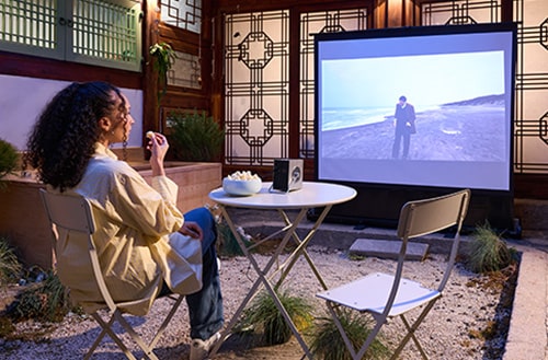 Un invité regarde un film projeté sur un écran avec CineBeam