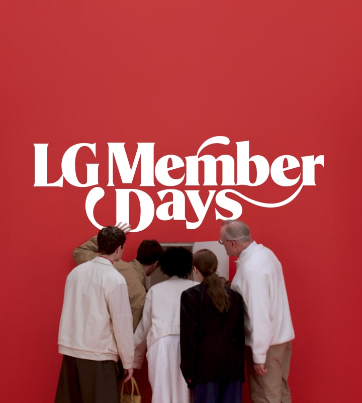 Várias pessoas estão olhando para uma pequena porta em uma parede vermelha, curiosas sobre o que é o evento LG Member Days