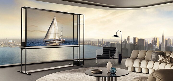 LG OLED T4 em um apartamento de cobertura. As janelas têm vista para o horizonte da cidade e para o oceano. A LG OLED T4 está no modo transparente, exibindo a imagem de um iate. Devido à posição da TV e à transparência da tela, o iate parece estar flutuando no oceano lá fora.