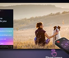 Um LG AI Magic Remote em frente à tela de uma LG TV. Uma saudação personalizada da LG AI é exibida na tela, com palavras-chave personalizadas baseadas na pesquisas do usuário e no histórico de visualização. Junto ao controle remoto há um ícone e um rótulo mostrando que a funcionalidade AI Concierge é facilmente acessível com um breve toque no botão AI. 