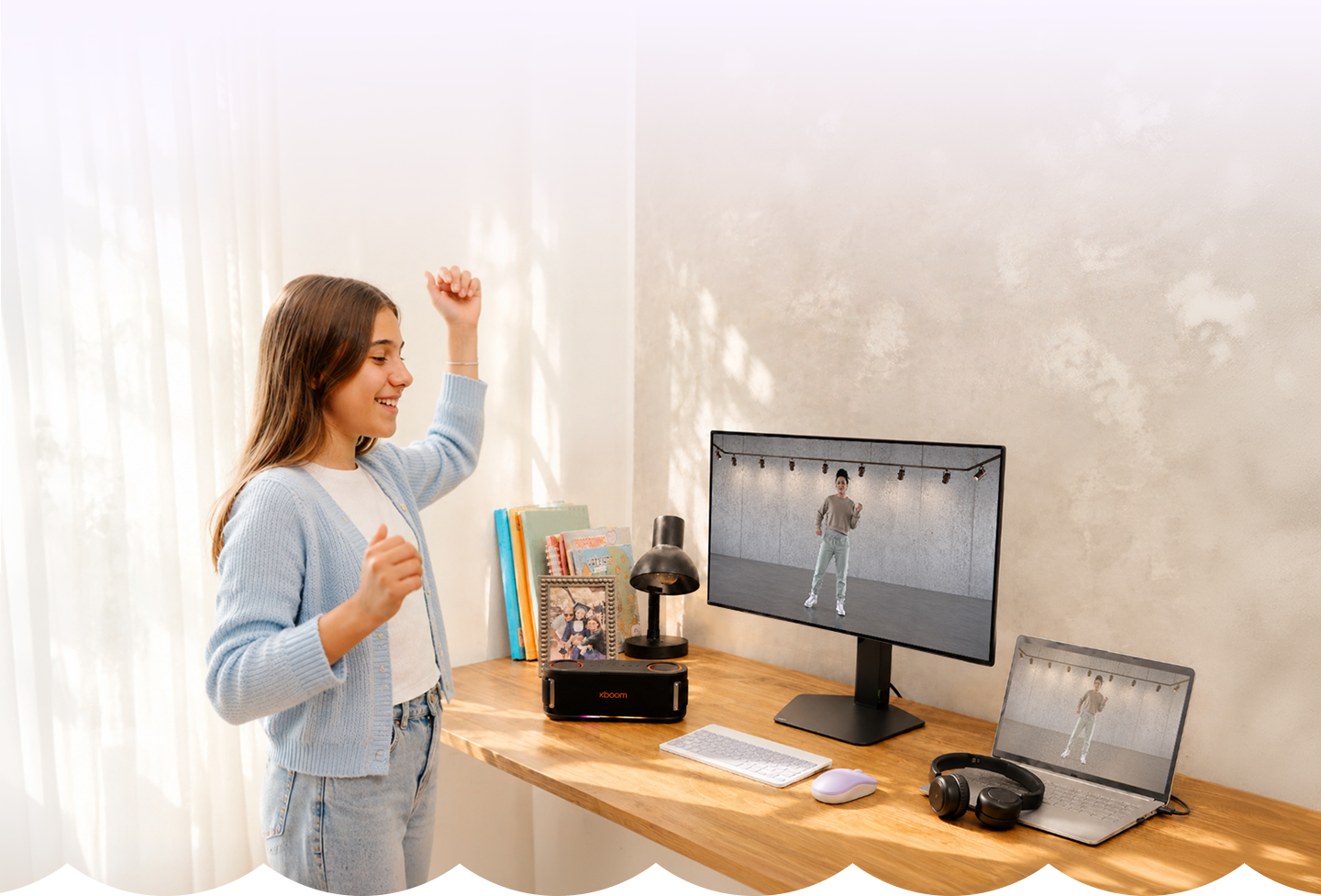 Uma Adolescente curtindo um jogo de dança no monitor LG, com a caixa de som XBOOM e um notebook na mesa