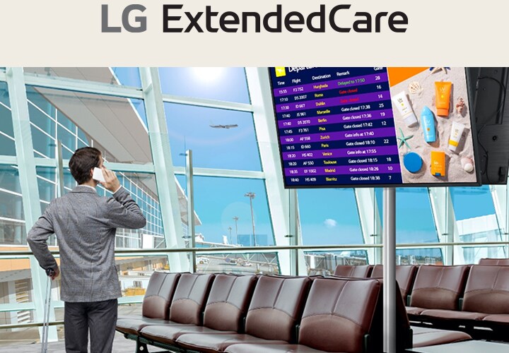 Um viajante está em um saguão de aeroporto, verificando seu telefone enquanto olha para um painel digital de embarque que exibe os horários dos voos. A cena destaca o uso moderno e eficiente da sinalização para atualizações em tempo real.