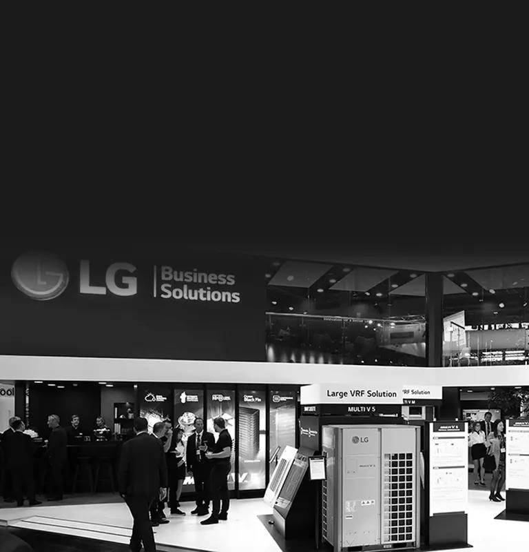 Modelos de soluções LG Ar Condicionado exibidos em um salão de exposições de dois andares enquanto os clientes olham ao redor e conversam entre si.