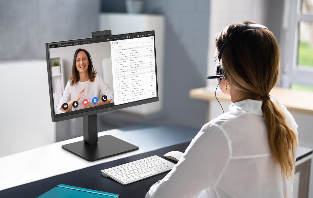 A woman wearing a headset is video conferencing with the built-in webcam.