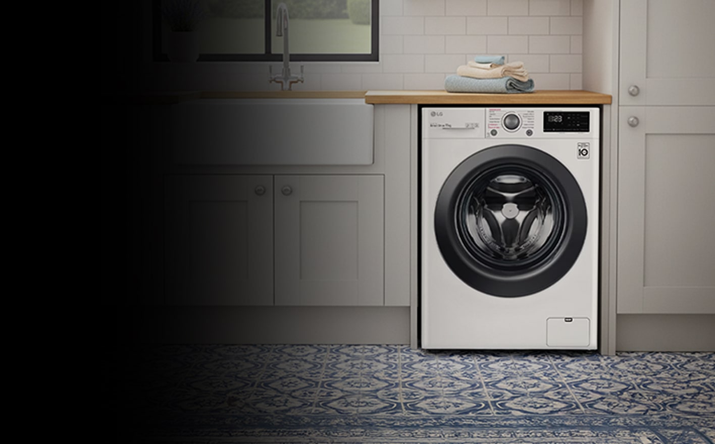 A white front-loading washing machine is placed between white-toned cabinets.