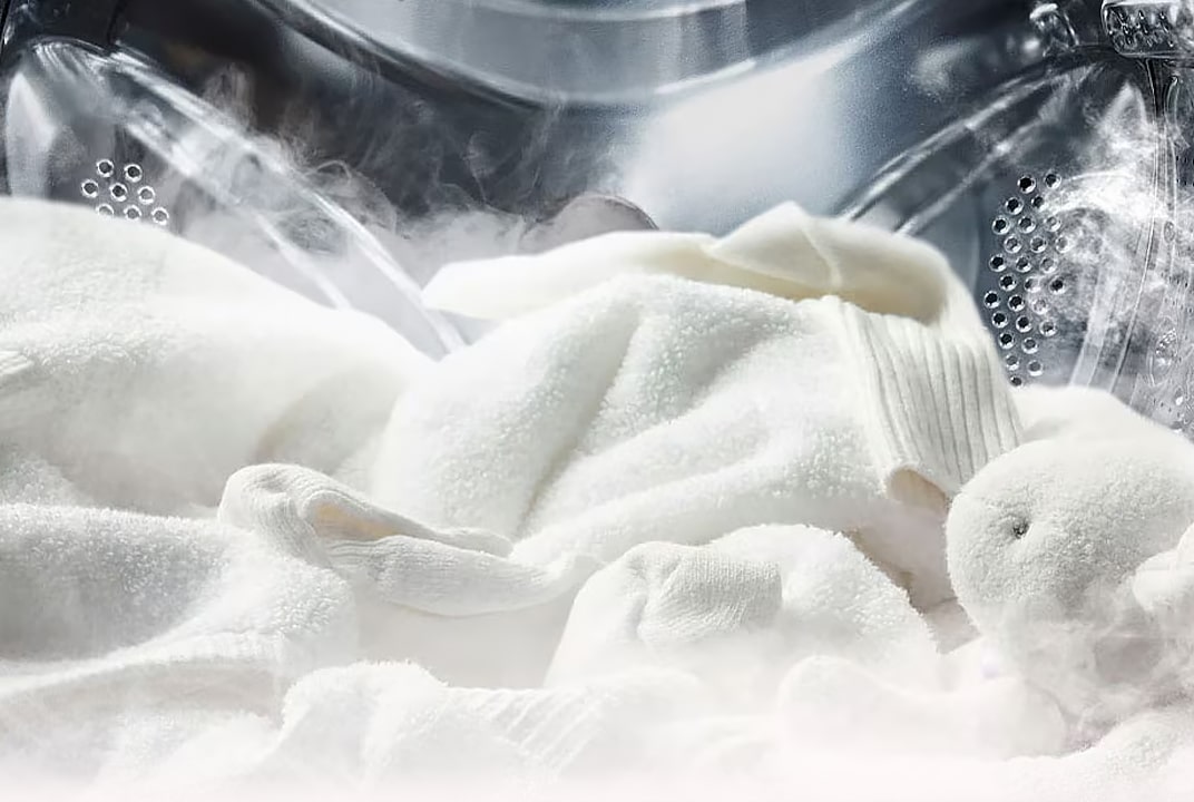 Tecidos brancos sendo lavados dentro do tambor da lavadora LG com vapor visível, destacando um ambiente de lavagem higiênico.
