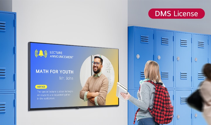 Essa imagem mostra um aluno visualizando conteúdo em uma tela de sinalização digital no corredor da escola. A notificação exibida diz: "MATH FOR YOUTH" (sessão especial de matemática para jovens), instruindo os alunos a se reunirem na sala de aula.