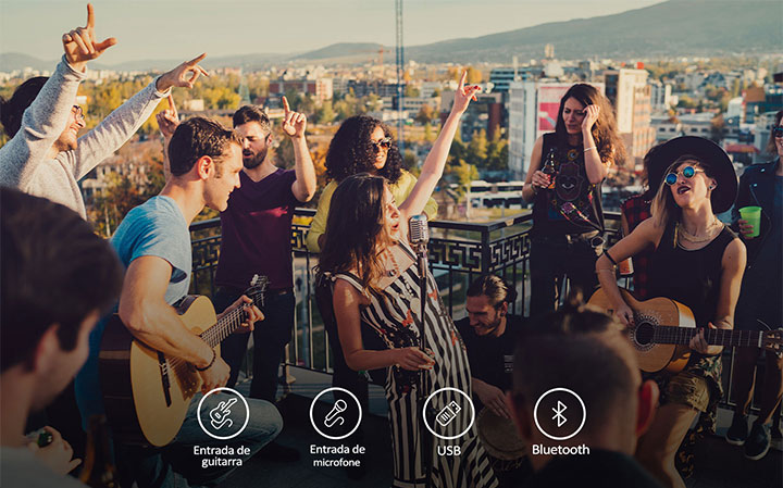 Há pessoas curtindo um show acústico com o LG XBOOM XL5T. Abaixo da imagem, há guitarras