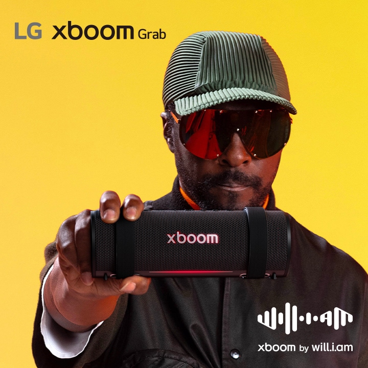 will.i.am de roupa preta e óculos de sol segurando uma LG xboom grab na sua frente.