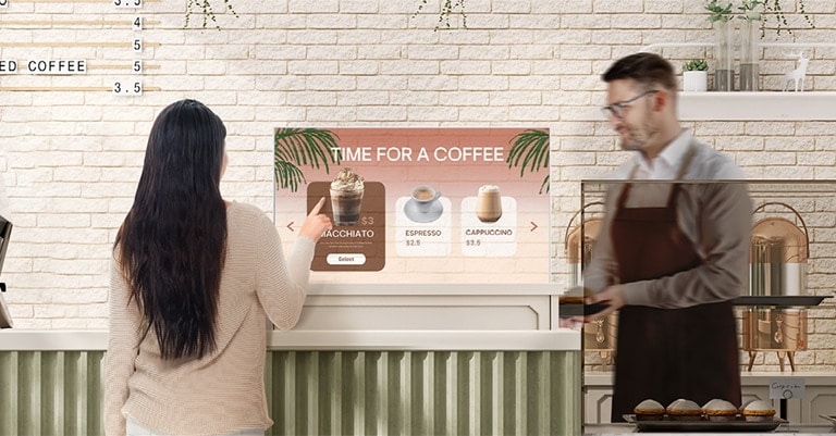 Em uma cafeteria, uma mulher está escolhendo um item do menu tocando na tela da OLED Transparente Signage.
