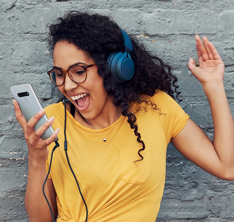 Mulher com fones ouvindo música alegremente.