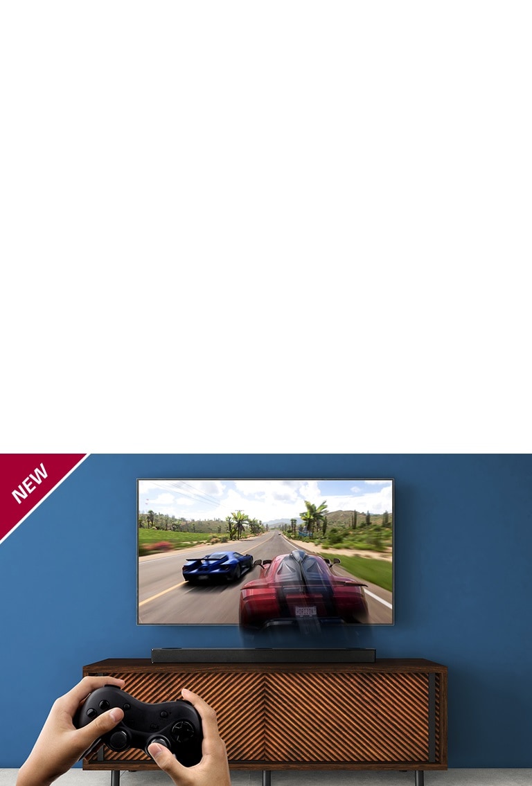 A TV LG está na parede, mostrando um game de corrida. A LG Sound Bar está colocada sobre um rack marrom, logo abaixo da TV LG. Um homem está segurando um joystick. O selo NOVO aparece no canto superior esquerdo.