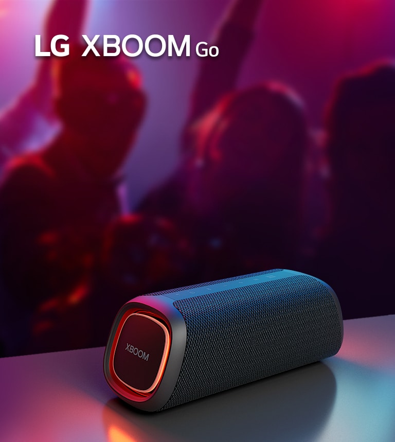 Caixa de som LG XBOOM Go em uma mesa com fundo de festa desfocado.