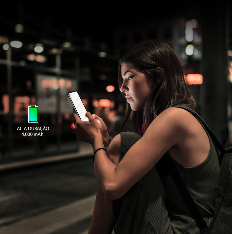 Mulher navegando na internet com seu smartphone à noite, numa estação de metrô, com bateria suficiente