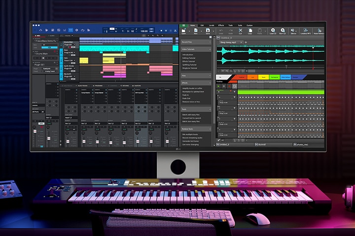 In a dark room with blue and violet lighting a UltraFine monitor stands with recording program on it. On the desk where it stands a keyboard, tablet, headphone and other accessories are placed.	