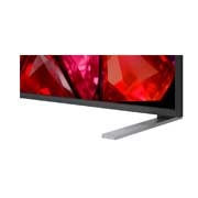 A LG Mini RGB evo AI MRGB85 está instalada na parede de uma sala de estar ampla e contemporânea, exibindo uma obra de arte abstrata vibrante com elementos multicoloridos em espiral.