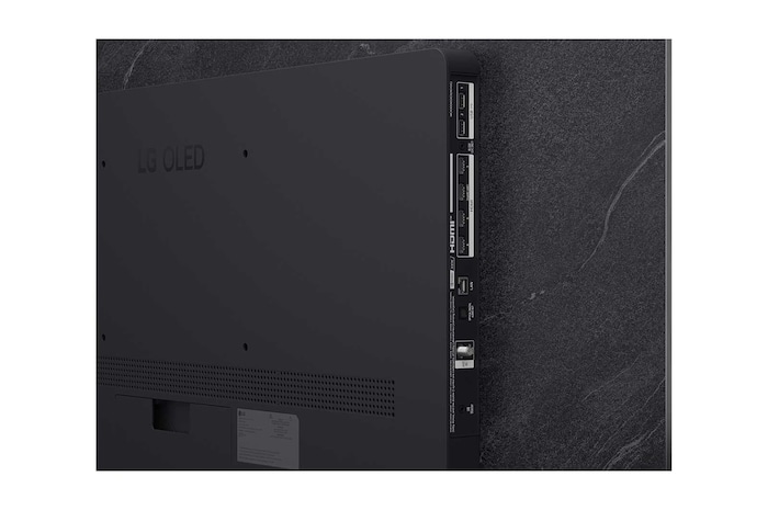 A LG OLED evo AI C6 está instalada na parede de uma sala de estar elegante, apresentando um design ultrafino com bordas estreitas, e exibe na tela uma paisagem urbana à beira do rio ao pôr do sol.