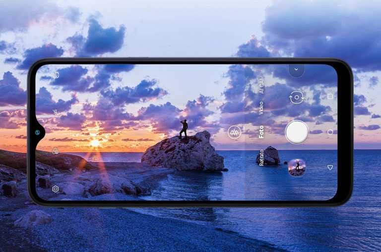 Smartphone fotografando um homem que contempla a praia ao entardecer.