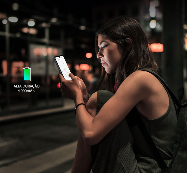 Mulher navegando na internet com seu smartphone à noite, numa estação de metrô, com bateria suficiente