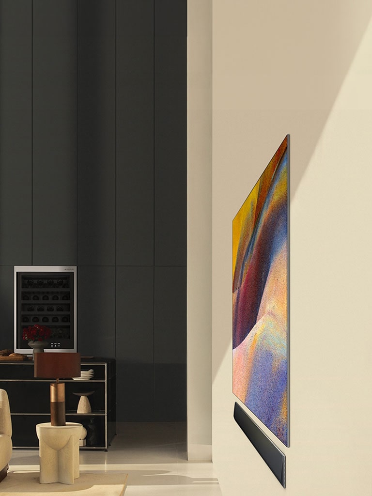 Vista lateral de uma LG OLED G4 exibindo uma elegante obra de arte abstrata e a soundbar LG instaladas na parede em uma sala de estar moderna.