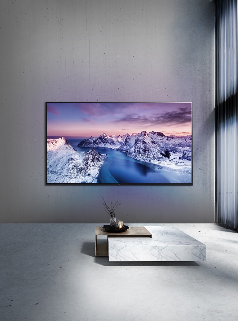 Uma TV UHD montada na parede, atrás de uma mesa com arranjo em estilo zen.