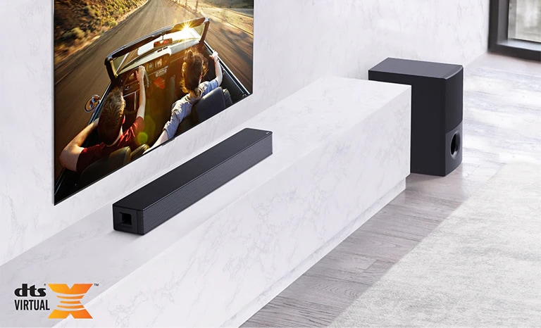 A TV está montada na parede, o LG Soundbar está por baixo numa prateleira branca de mármore com um subwoofer à direita. A TV mostra um casal num automóvel.