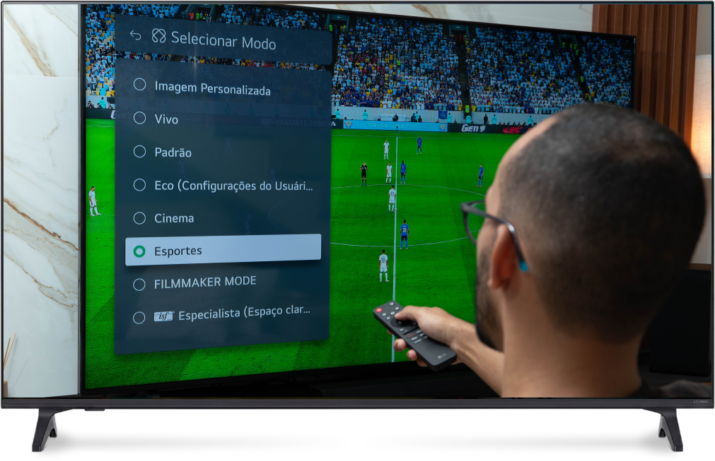 Rafinha usando o controle remoto para selecionar o modo Esportes no menu de configurações de imagem