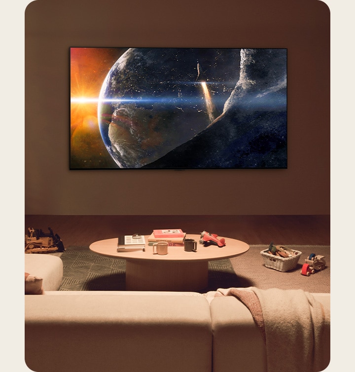 Uma família sentada no chão de uma sala de estar com pouca luz, ao lado de uma pequena mesa, olhando para cima para uma TV LG montada na parede, mostrando a Terra do espaço.