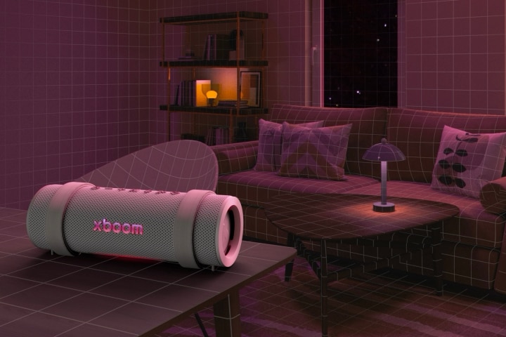 Em uma sala com iluminação rosa, um sofá branco e uma mesa estão posicionados atrás. Na frente, o xboom Grab está posicionado sobre uma mesa retangular branca.