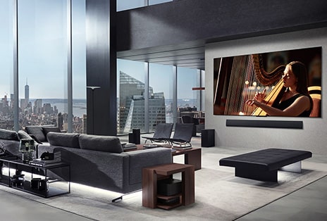 Living room with an LG True Wireless TV and LG Soundbar that's wall-mounted. The Zero Connect Box is barely seen under a side table by the couch, showing how it can easily be placed anywhere. The whole living room's layout is visually neat and tidy.