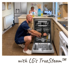 A man kneels on the floor, loading dishes into an open LG dishwasher. [with LG's TrueSteam™]