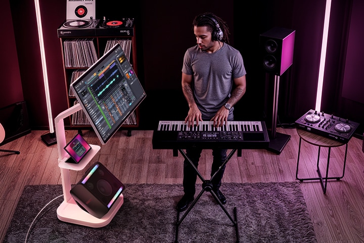 Music producer editing audio on LG Smart Monitor Swing via tablet screen mirroring, using Swing Stand and Swing Stand Plate with XBOOM Stage 301 and tablet neatly arranged in a home studio setup