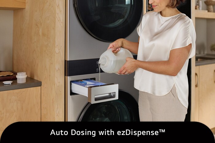 The LG WashTower SWWE50N3 in Stainless Steel, illustrating a user refilling the ezDispense™ Auto Dosing System, emphasizing the convenience of automatic detergent and softener dispensing.