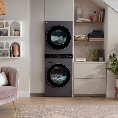 The LG WashTower WKHC252HBA in Black Steel, showcasing its premium, space-saving design and flexible installation, blending seamlessly into a modern living area under a staircase.