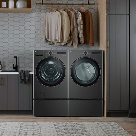 The Black Steel LG 7.4 cu.ft. dryer DLEX6500B, installed side-by-side with a matching washer on pedestals in a modern laundry room.