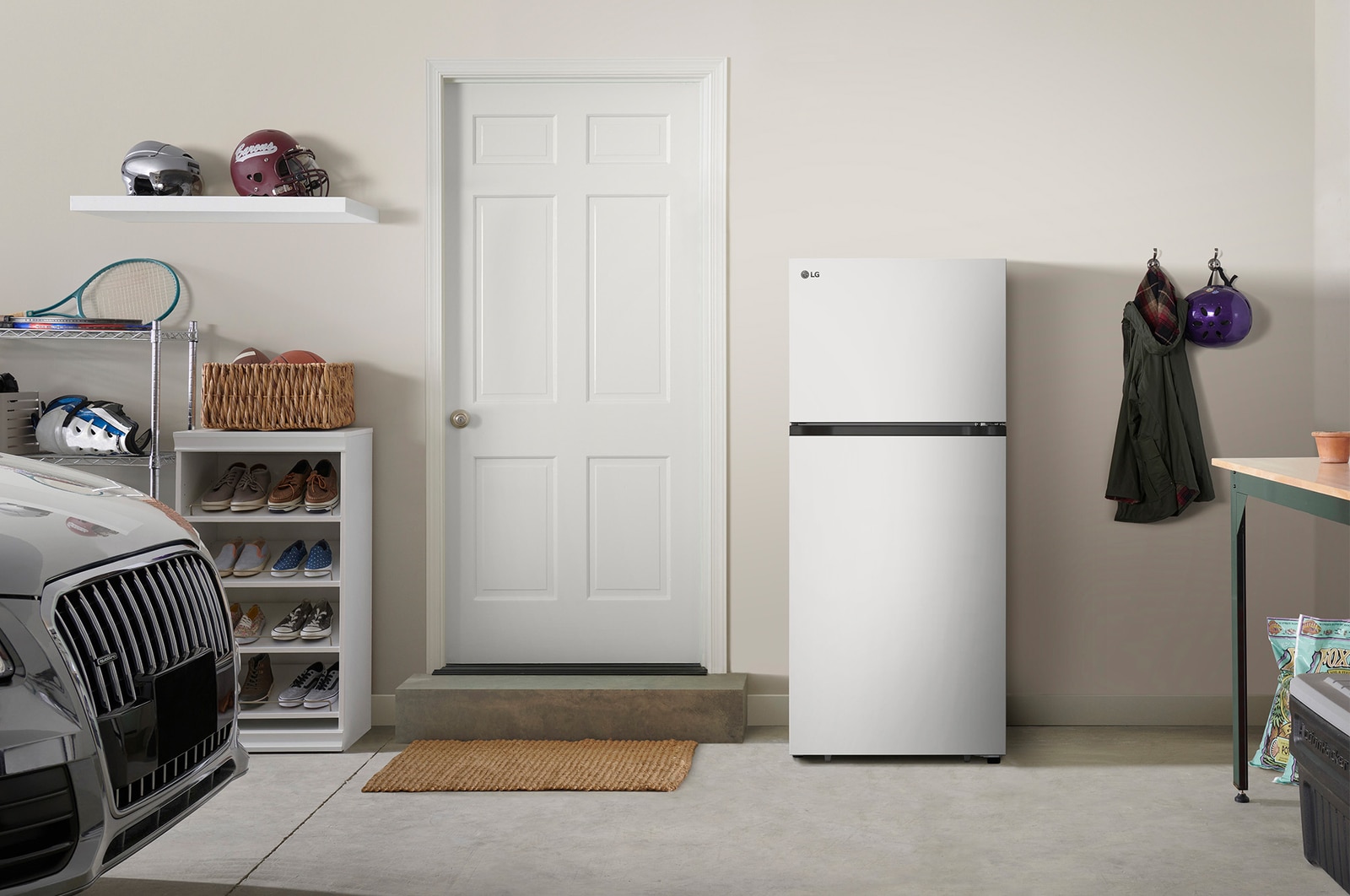 The white finish LG 28-inch 18 cu.ft. Top Freezer Refrigerator LT18S2100W, shown placed in a garage setting.