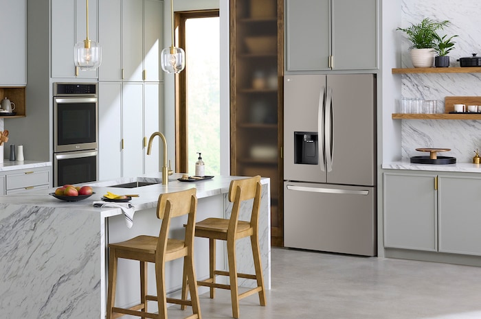The PrintProof™ Stainless Steel LG 36-inch 26 cu.ft. French Door Refrigerator LRFXC2606S with ice & water dispenser, shown in a bright modern kitchen.