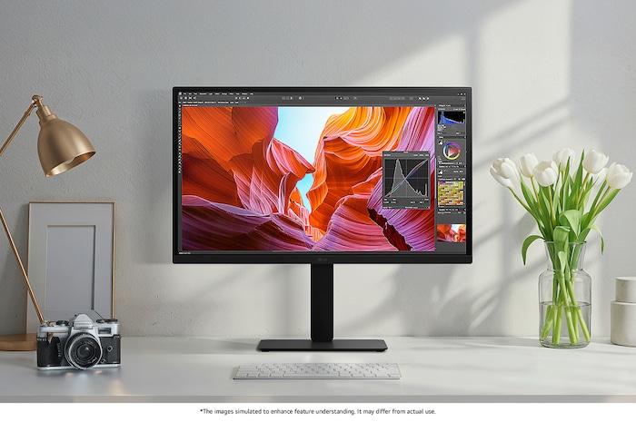 The LG Monitor 27BA45U in a matte black finish, featuring DCI-P3 90% colour gamut, is shown in a stylish studio being used for professional photo editing and design work.