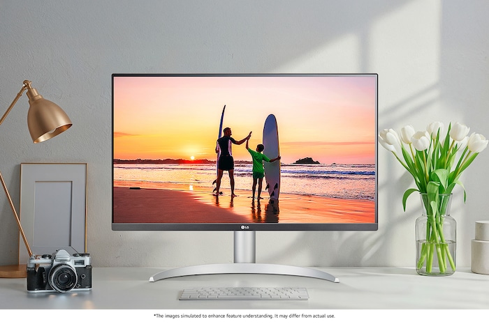 LG Monitor 27UP650K in a white/silver design positioned on a desk, displaying a vibrant, high-resolution image of a beach sunset and highlighting the superb picture quality.