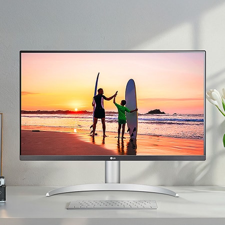 LG Monitor 27UP650K in a white/silver design positioned on a desk, displaying a vibrant, high-resolution image of a beach sunset and highlighting the superb picture quality.
