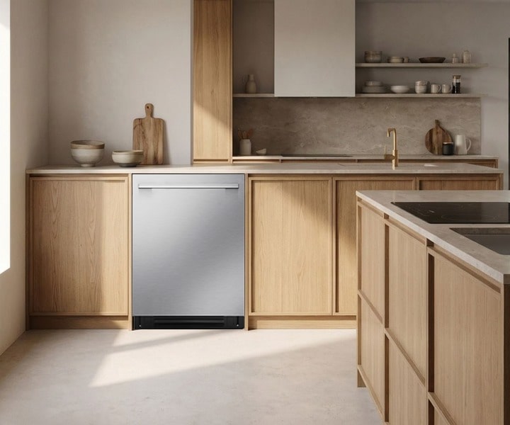 Stainless steel dishwasher integrated into light wood cabinetry in a modern kitchen with a large island and sink.