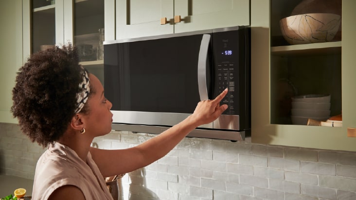 An LG built-in black oven sits in white cabinetry in a modern kitchen with marble island and striped blind.