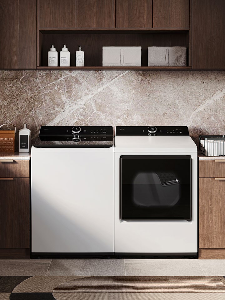 LG White top load washing machine with black control pane and a white dryer set in a cupboards and bright window on the left.