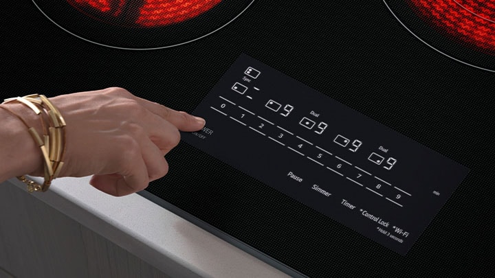Close-up of a black glass electric cooktop featuring SmoothTouch glass touch controls and a digital display.