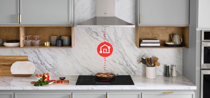 Black LG induction cooktop with five burners and a smartphone displaying the ThinQ app for remote monitoring.