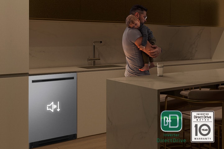 Man holding a sleeping child while a quiet dishwasher runs in the background